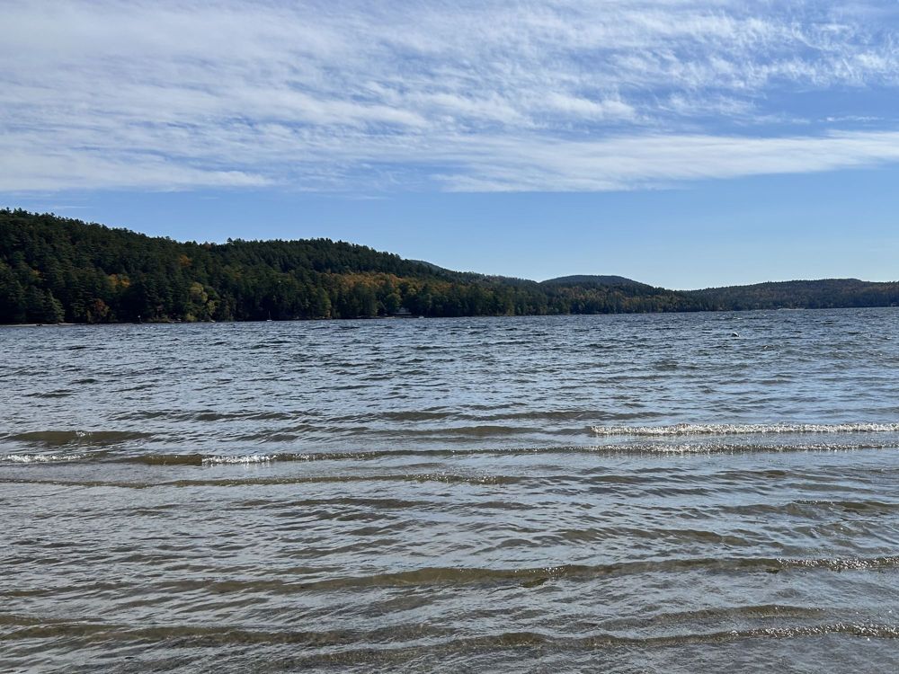 A mountain lake under a wide sky, with wooded hills along the far shore
